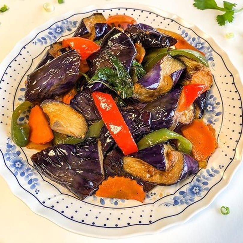 Thai Nary BBQ's stir-fried eggplant with bell peppers, carrots, and basil on a decorative plate.