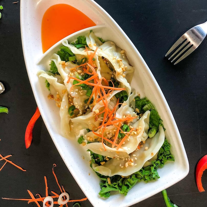 Thai Nary BBQ's steamed dumplings, garnished with carrots, scallions, and sesame seeds, served with orange sauce.