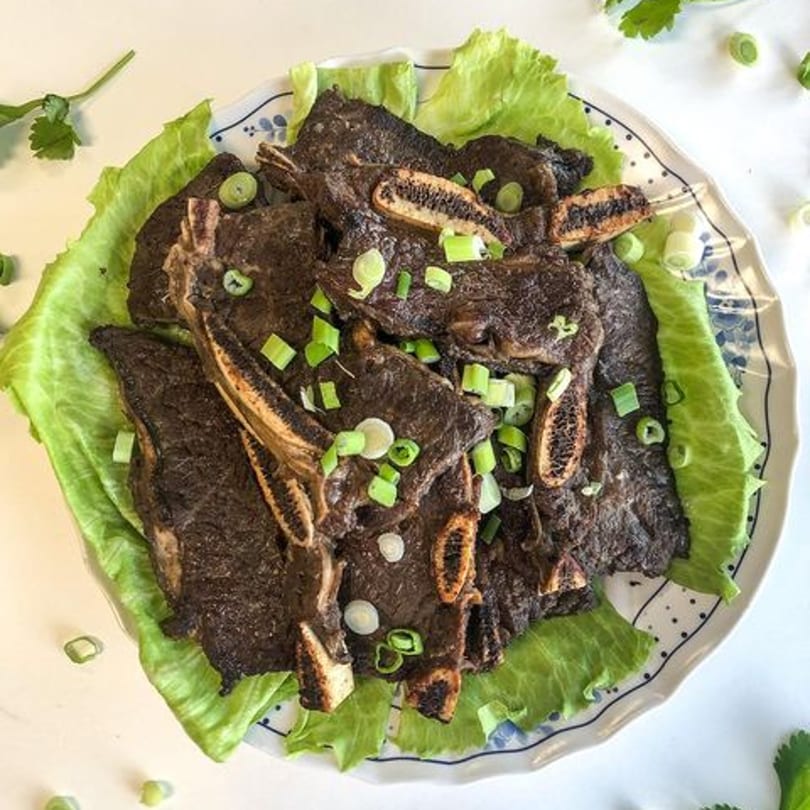 Thai Nary BBQ's grilled short ribs, garnished with green onions, served on a bed of lettuce.